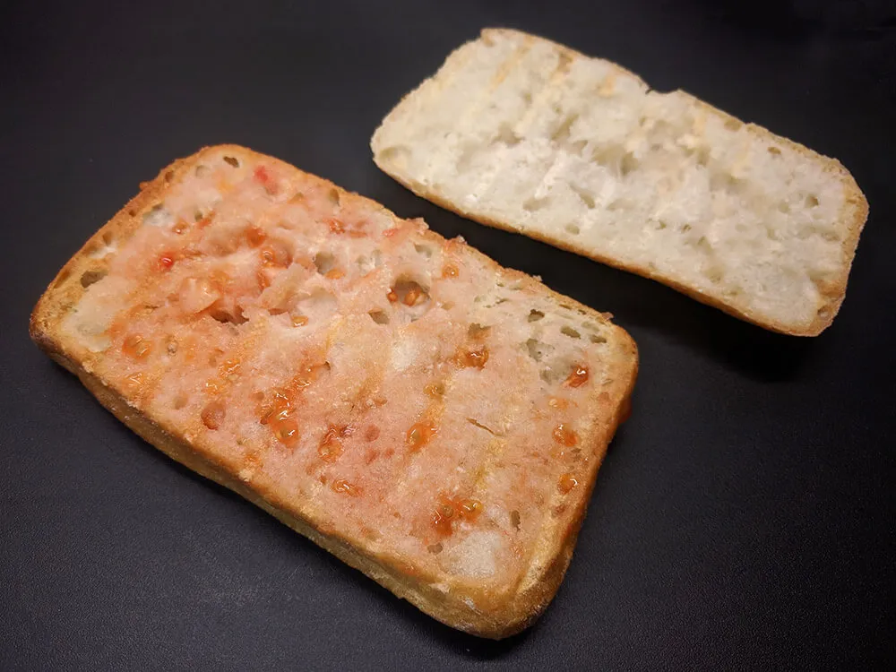 Chapata cortada, tostada y untada con tomate.