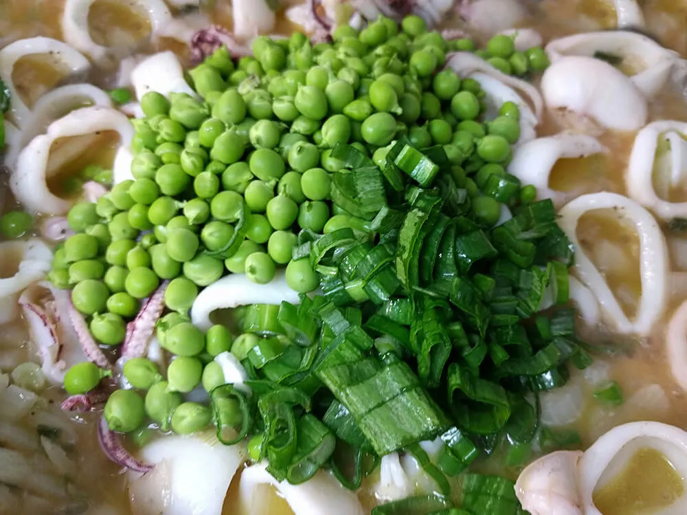 Cebolla tierna y calamares cocinados con guisantes frescos