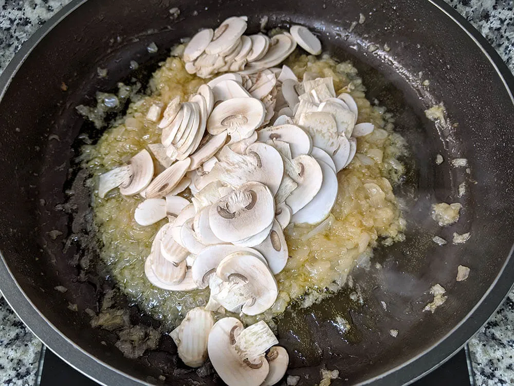 Cebolla y diente de ajo rehogados y champiñones laminados.