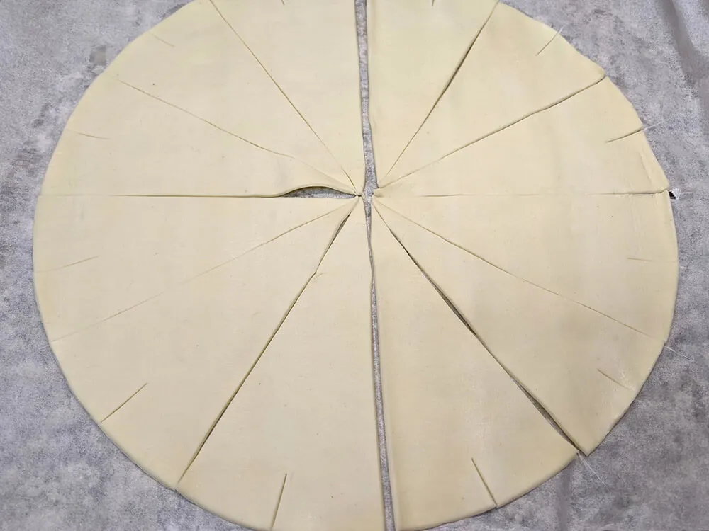 Masa de hojaldre redonda cortada a triángulos.