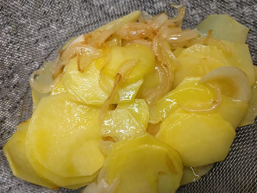 Patatas y cebollas escurriendo el aceite