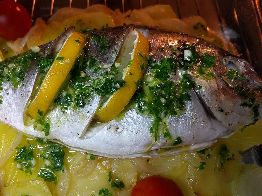 Dorada al horno napada con aceite de ajo y perejil