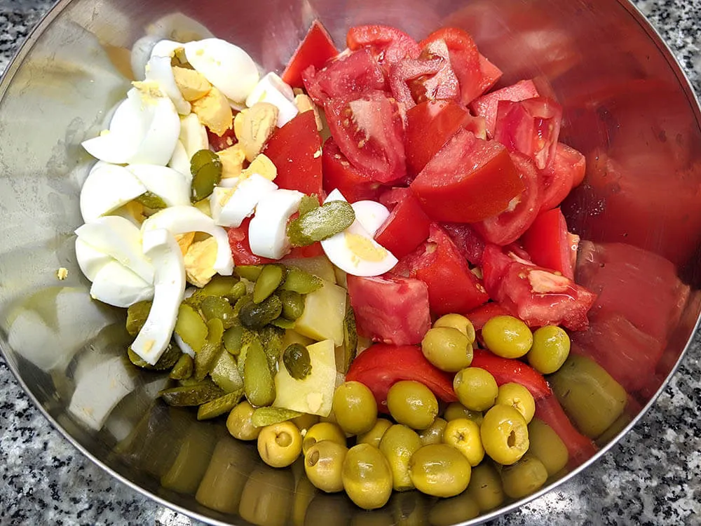 Patata y huevos cocidos, tomate, olivas y pepinillos.