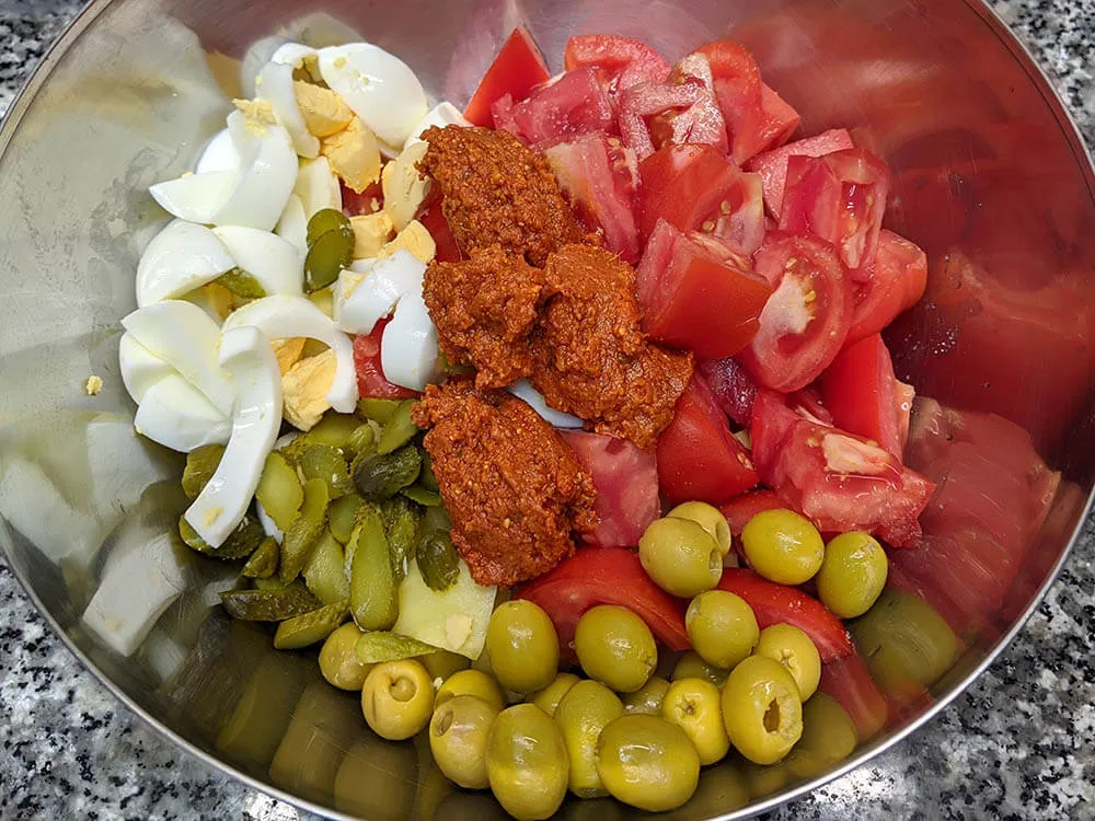 Patata y huevos cocidos, tomate, olivas, pepinillos y salsa pesto rosso.