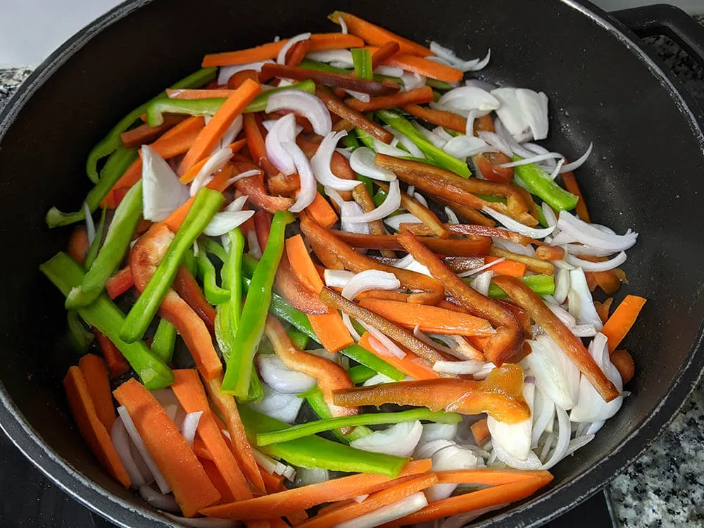 Pimientos verde y rojo, zanahoria y cebolla en sartén.