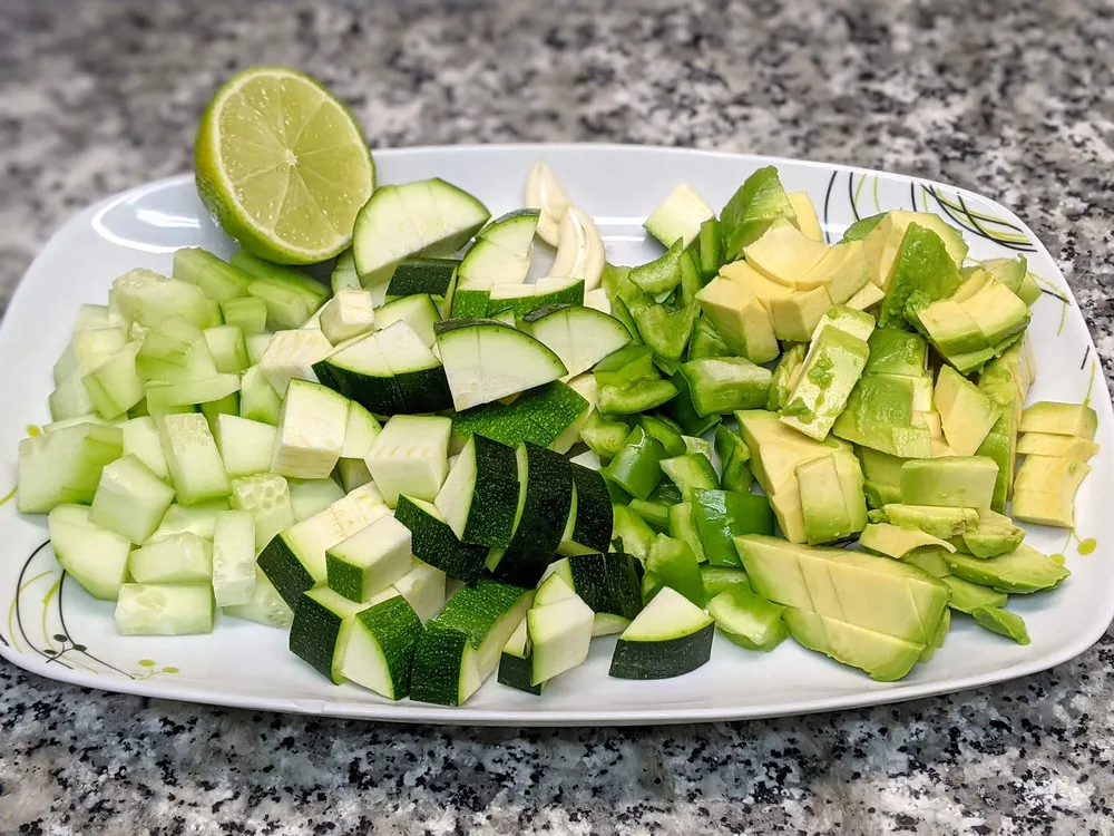 Dados de aguacate, pepino, calabacín y pimiento verde. Lima y diente de ajo.
