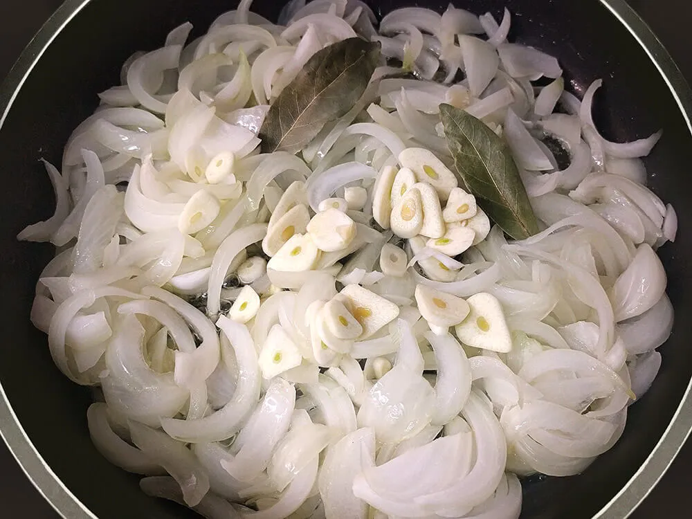 Cebolla pochándose con ajo laminado y laurel.