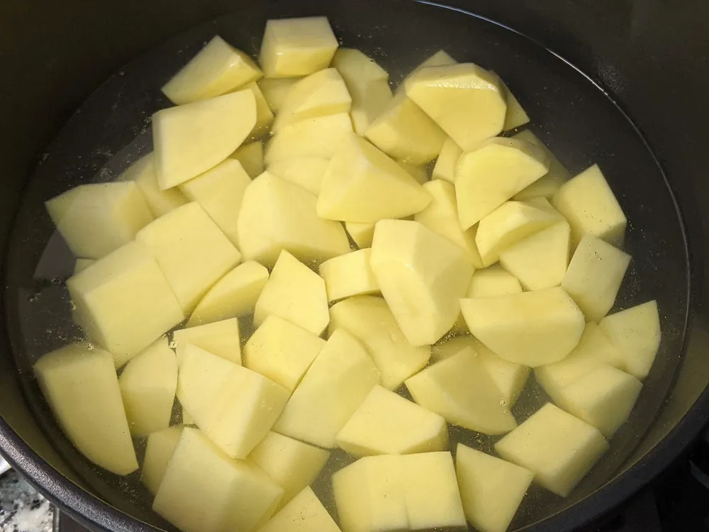 Patatas peladas y cortadas en olla.
