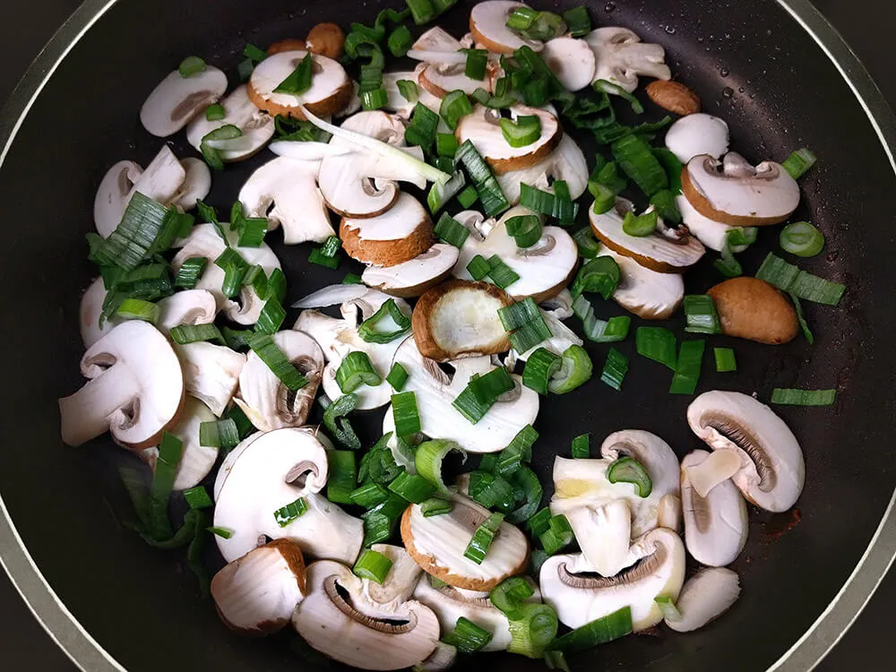 Champiñones y tallo de cebolleta rehogándose