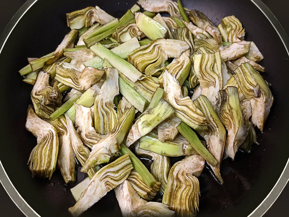 Alcachofas cortadas en sartén.