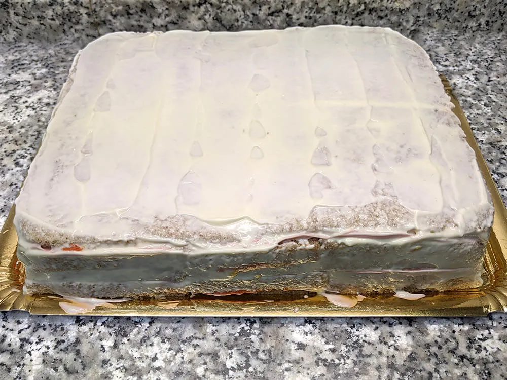 Pastel de pan de molde untado con mayonesa, lechuga y cherrys.