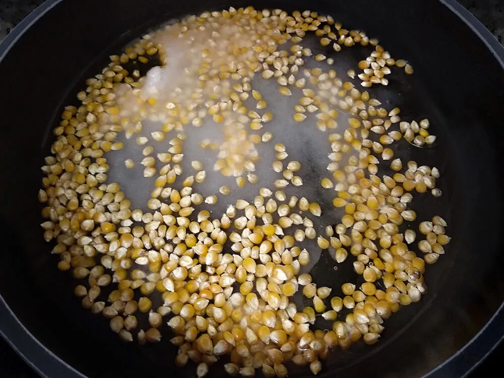 Cazuela con maíz, azúcar, agua y aceite de girasol en ebullición.