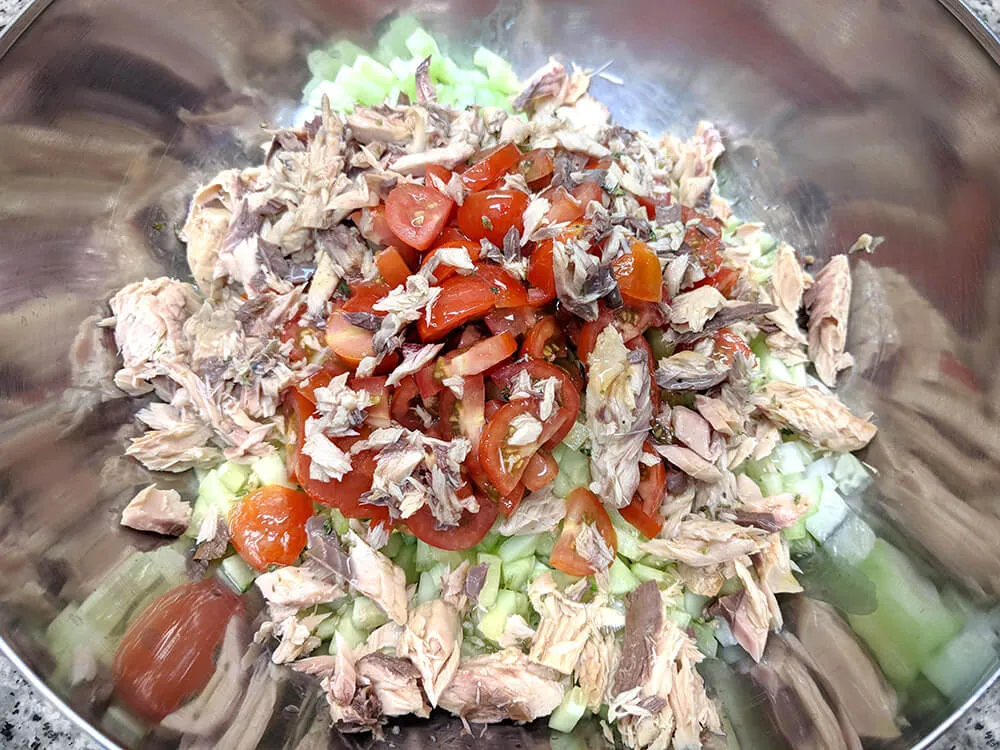 Pepino, pimiento verde, pimiento rojo, cebolla tierna, tomates cherry, pepinillos en vinagre, olivas cortados y caballa desmenuzada.