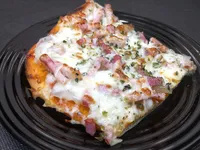 Porción de pizza de cebolla, mozzarella y bacon