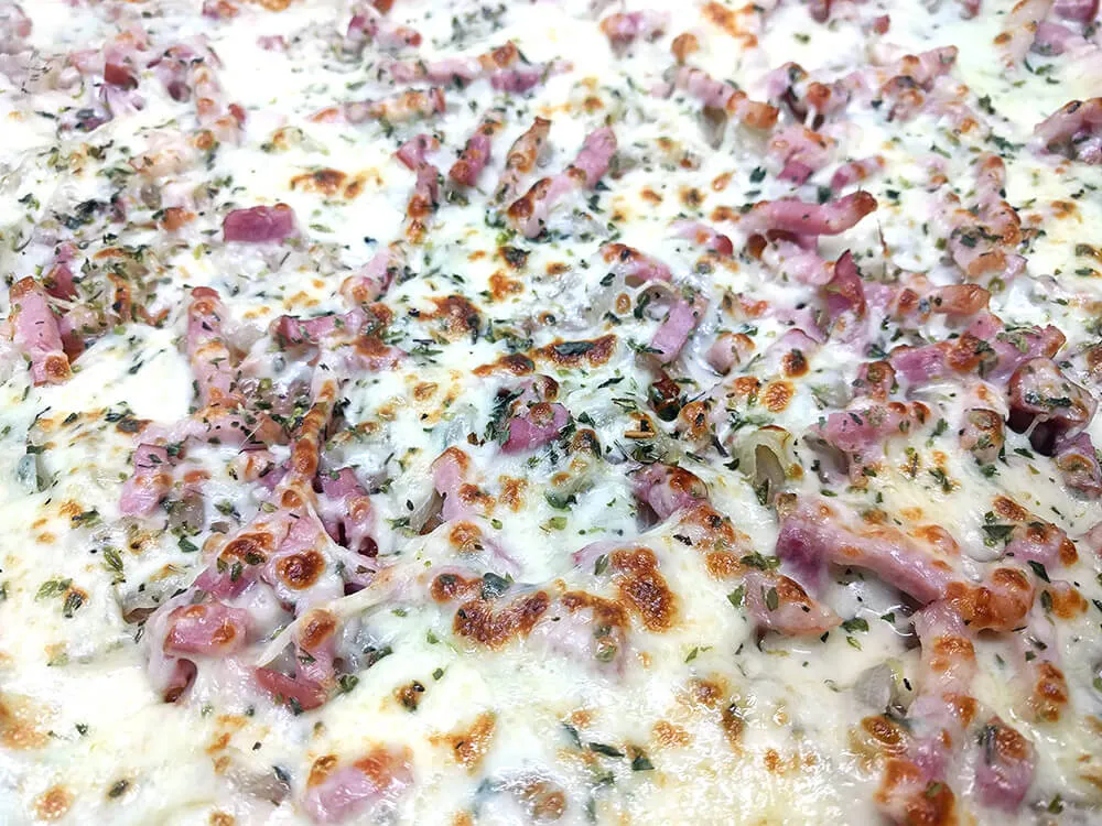 Pizza de cebolla, mozzarella y bacon gratinada.
