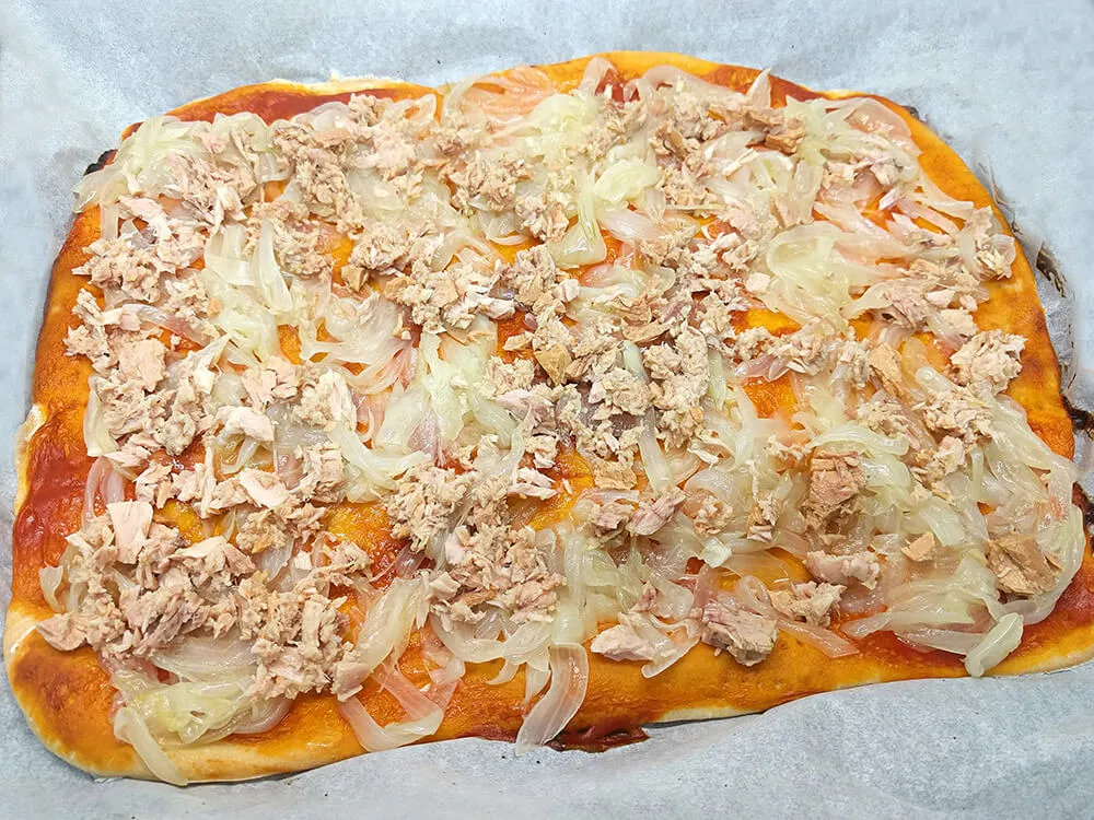 Base de pizza con cebolla frita y atún.