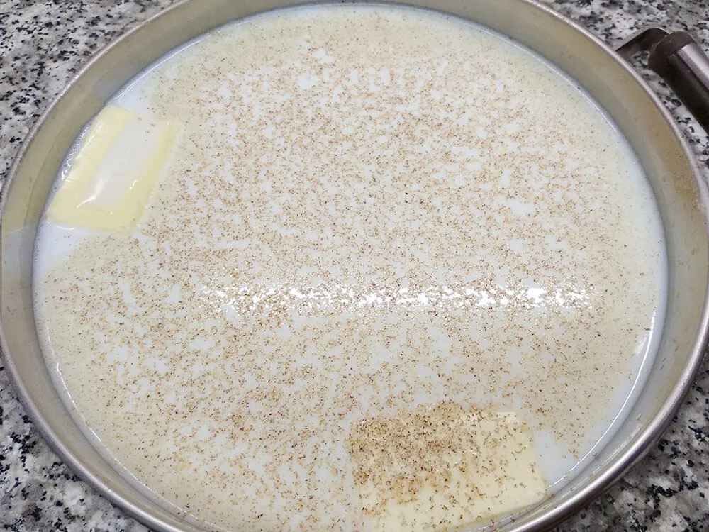Leche, agua, mantequilla, pimienta, nuez moscada y sal en cazuela.