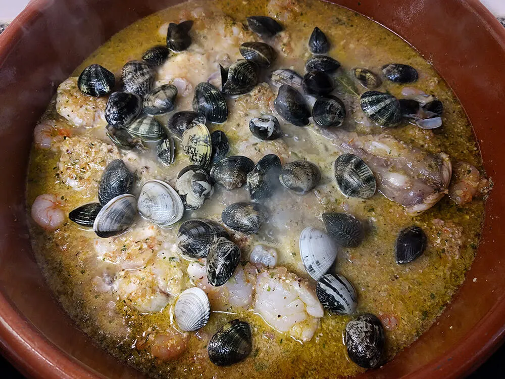 Caldo de pescado con sofrito, rape, gambitas y almejas.