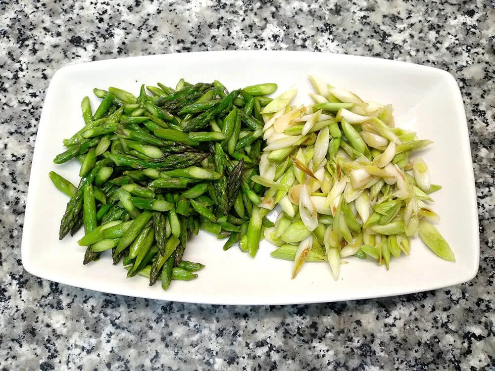 Espárragos verdes y ajos tiernos con aceite de ajo y perejil.