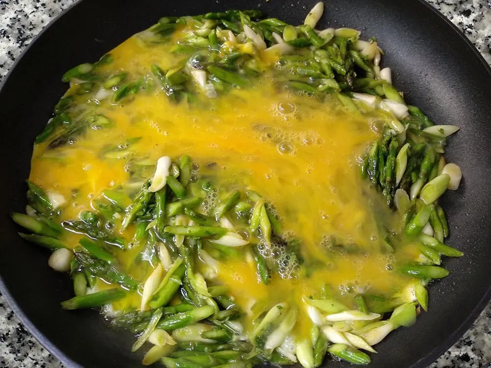 Añadimos los huevos batidos a la sartén y cocinamos todo junto hasta que el huevo cuaje a nuestro gusto.