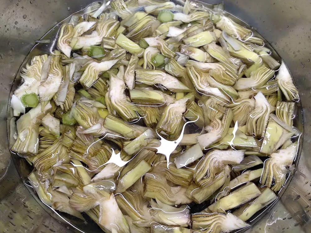 Alcachofas peladas y cortadas en remojo.