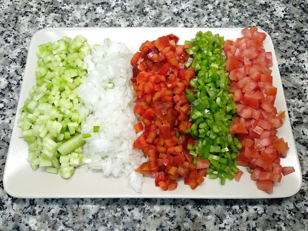 Daditos de pepino, cebolleta, pimientos rojo y verde y tomate.
