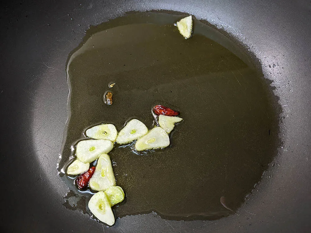 Sartén con diente de ajo laminado y guindillas.