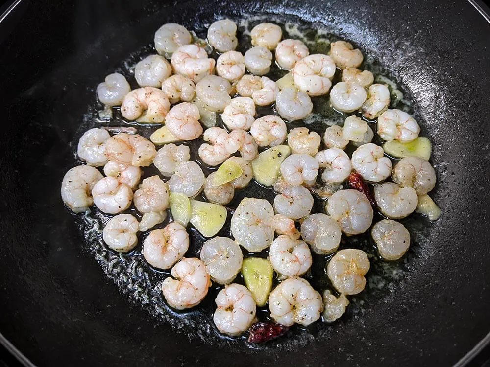 Sartén con diente de ajo laminado, guindillas y gambitas.