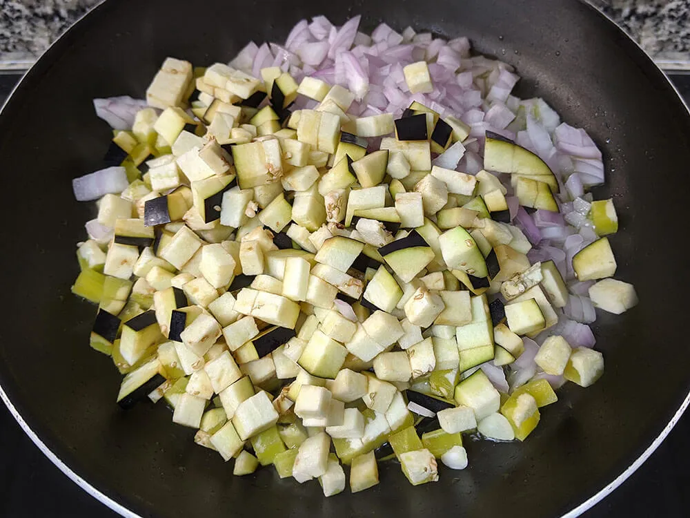 Cebolla y berenjena a daditos en sartén.